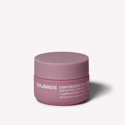 Un barattolo rosa di Solawave LightBoost Eye Cream è posto al centro di uno sfondo neutro, che mette in risalto la sua tecnologia LightBoost e la sua formula a base di collagene vegano per amplificare e rassodare le proprietà della vostra routine di cura della pelle.